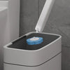 A white toilet brush and holder set with a blue cleaning brush visible on the lid.