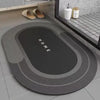 A round, dark gray anti-slip floor mat with concentric rings is displayed on a light tiled floor.