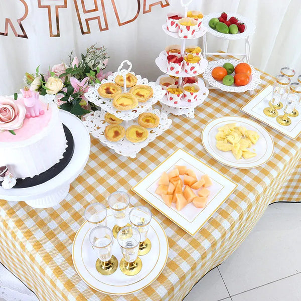 A table display featuring various fruits and candies arranged on white and pink tiered dessert stands.