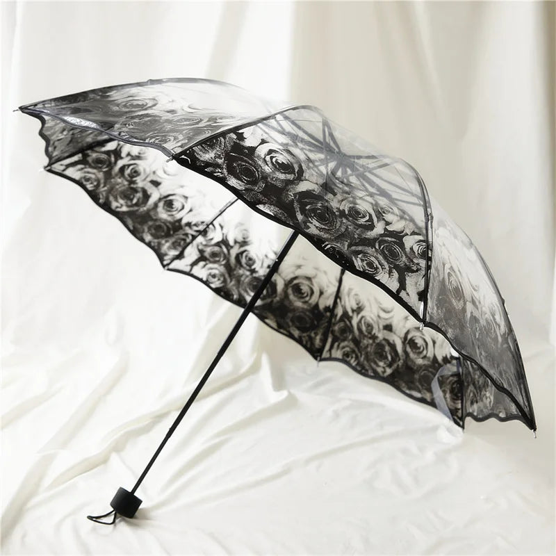 A black retro transparent folding umbrella with a floral pattern is shown open against a white background.