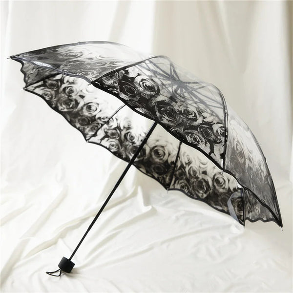 A black retro transparent folding umbrella with a floral pattern is shown open against a white background.