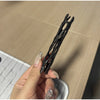A hand holds a black willow stick night light projector against a light wood background.