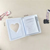 Álbum de fotos de plástico transparente con compartimento en forma de corazón y una sección rectangular, junto a pequeños ado
