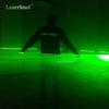 Una persona está en una habitación oscura iluminada por un haz de láser verde brillante de un módulo Laserland.