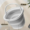 A white collapsible water bucket with a handle is shown pouring water onto a flat surface.