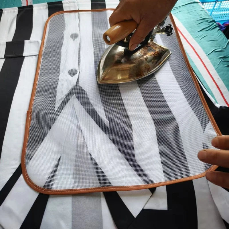 Une main utilise un fer en métal sur un coussin de protection à repasser blanc avec des rayures noires et grises.