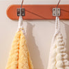 Two fluffy bath towels, one yellow and one white, are hanging on a wooden rack.
