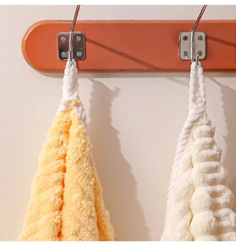 Two fluffy bath towels, one yellow and one white, are hanging on a wooden rack.