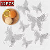 Twelve silver decorative butterfly wall stickers displayed next to a slice of orange and an orange sphere.