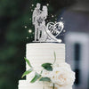 A white wedding cake with a crystal rhinestone Mr & Mrs topper and white roses and green leaves.