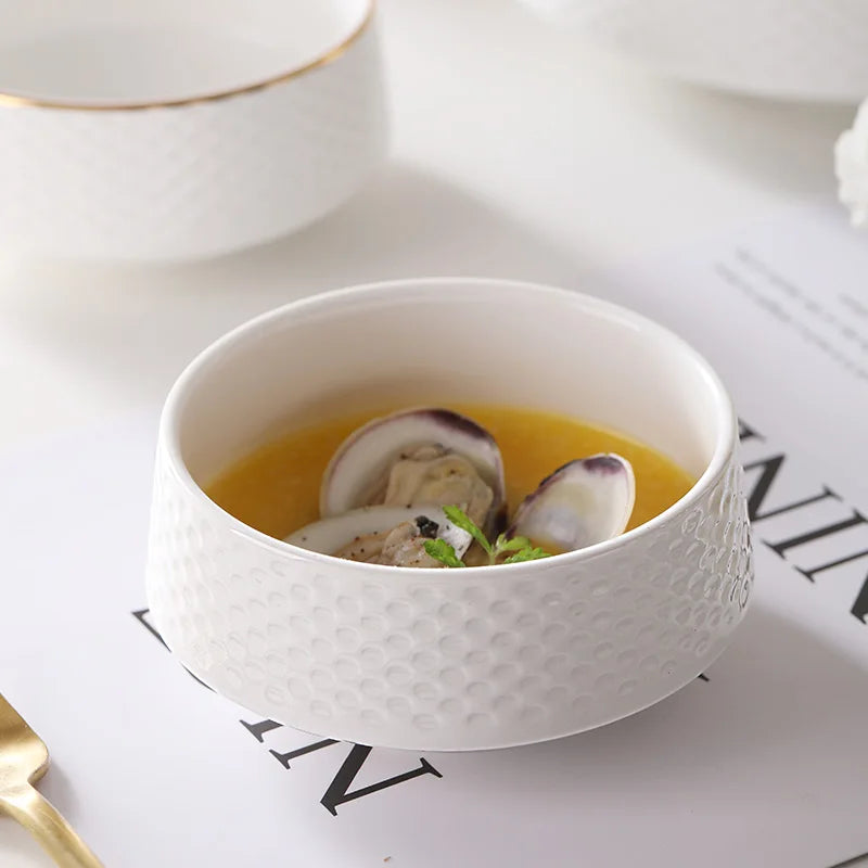 A white ceramic soup bowl filled with a light yellow broth and slices of white and purple vegetables.