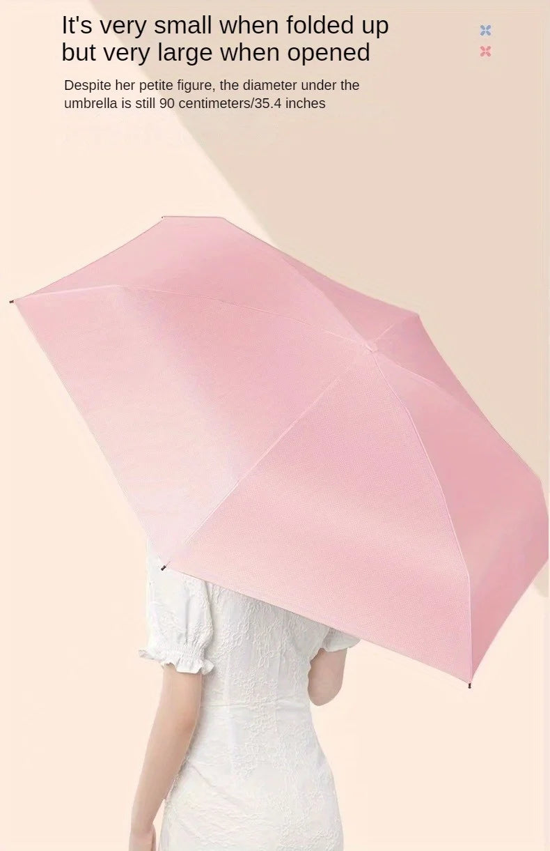 A pink folding umbrella is held by a person, demonstrating its compact and expanded size.