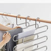 A hand is hanging a striped garment on a multi-layer stainless steel clothes rack.