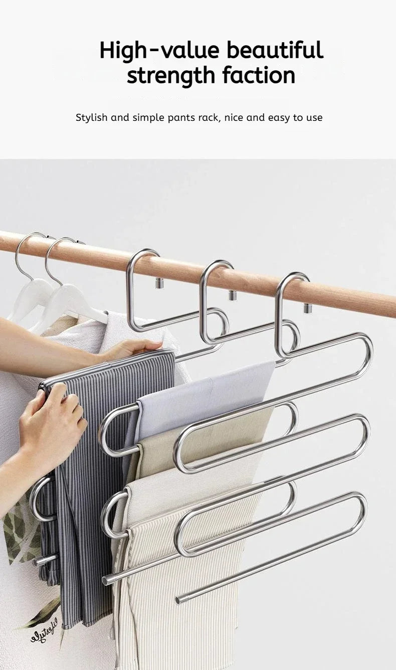 A hand is hanging a striped garment on a multi-layer stainless steel clothes rack.