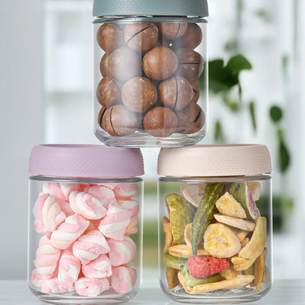 Three glass meal prep jars with airtight lids containing nuts, marshmallows, and dried fruit.