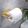 A gold-toned no-drill adhesive paper towel holder with a white roll mounted on a gray wall.