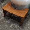 A wooden squat stool with a curved seat and four legs is shown on a marbled floor.