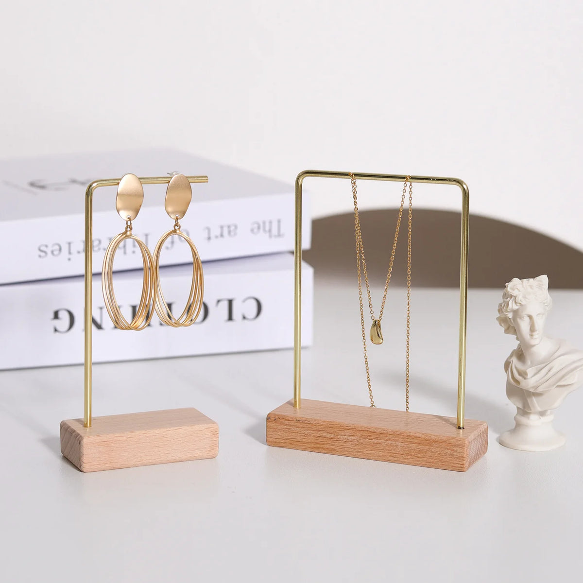 A gold-toned jewelry display rack featuring wooden stands holding pairs of hoop and pendant earrings.