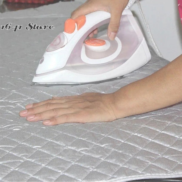 A hand is using a white folding ironing mat with orange accents to press a flat surface.