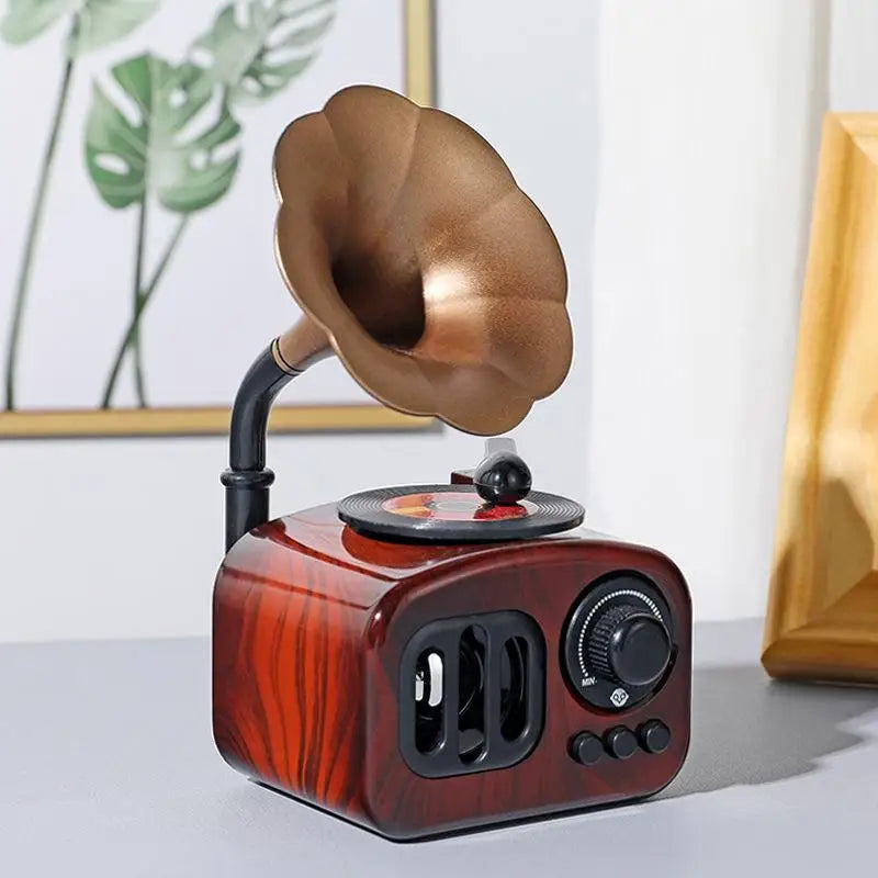 A wooden retro phonograph music box with a bronze horn is displayed on a light surface.