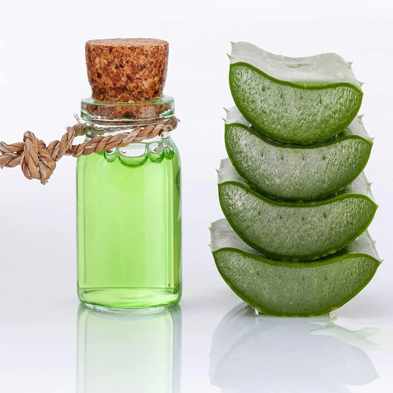 Fiole en verre remplie de liquide vert et un bouchon en liège à côté de plusieurs feuilles de plante vertes coupées.