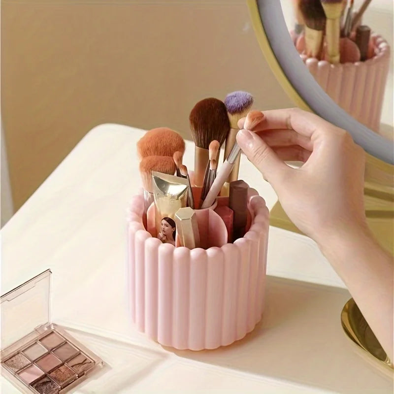 A hand is arranging various makeup brushes inside a pink cylindrical organizer for storage.