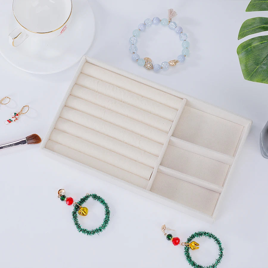 A velvet jewelry organizer tray with a drawer displaying various beaded and gold jewelry items.