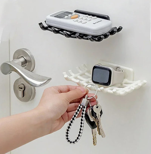 A hand is holding a set of keys and a small electronic device, positioned near a wall mounted soap dish rack.
