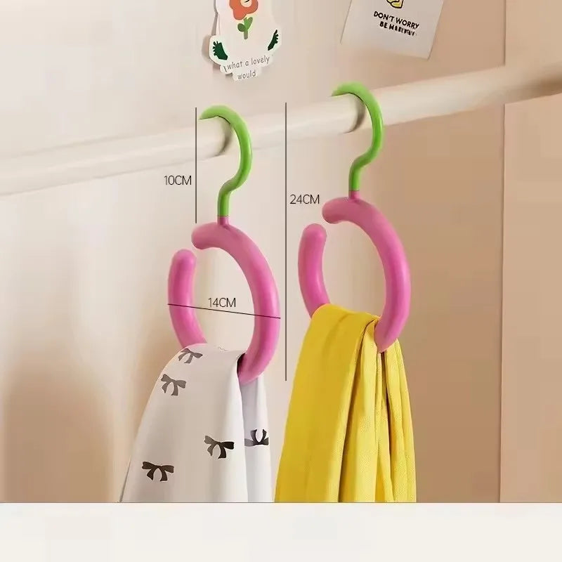 Un ensemble de cintres pour manteaux et chapeaux roses avec des crochets verts exposés contre un mur blanc.