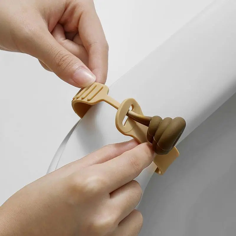A hand is lifting a portable toilet lid using a plastic lifter tool.