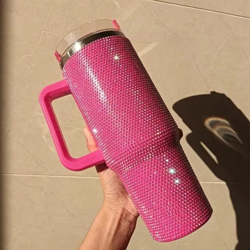 Una mano sostiene un vaso aislado de strass rosa brillante con una pajita contra un fondo claro.
