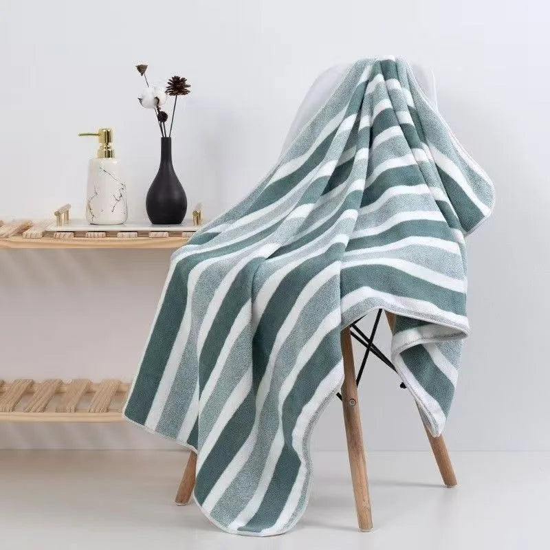 A folded gray and white striped microfiber bath towel draped over a wooden stand.