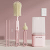 A set of pink silicone bottle brushes and a drying rack displayed on a light surface.