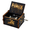An antique wooden hand crank music box with a lid engraved 'May the Force be with you' and a small metal mechanism.