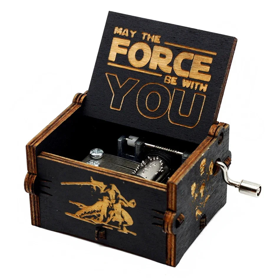 An antique wooden hand crank music box with a lid engraved 'May the Force be with you' and a small metal mechanism.