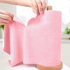 A hand is holding a pink reusable microfiber cleaning cloth rolled on a wooden spindle.