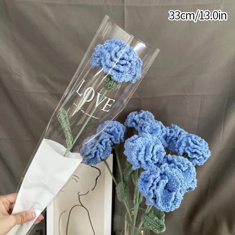 Un vase en verre clair contient un bouquet de cœurs de coton faits main bleu et vert.