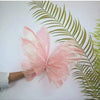 Pink glittery 3D simulated butterfly decoration resting on a green palm leaf.