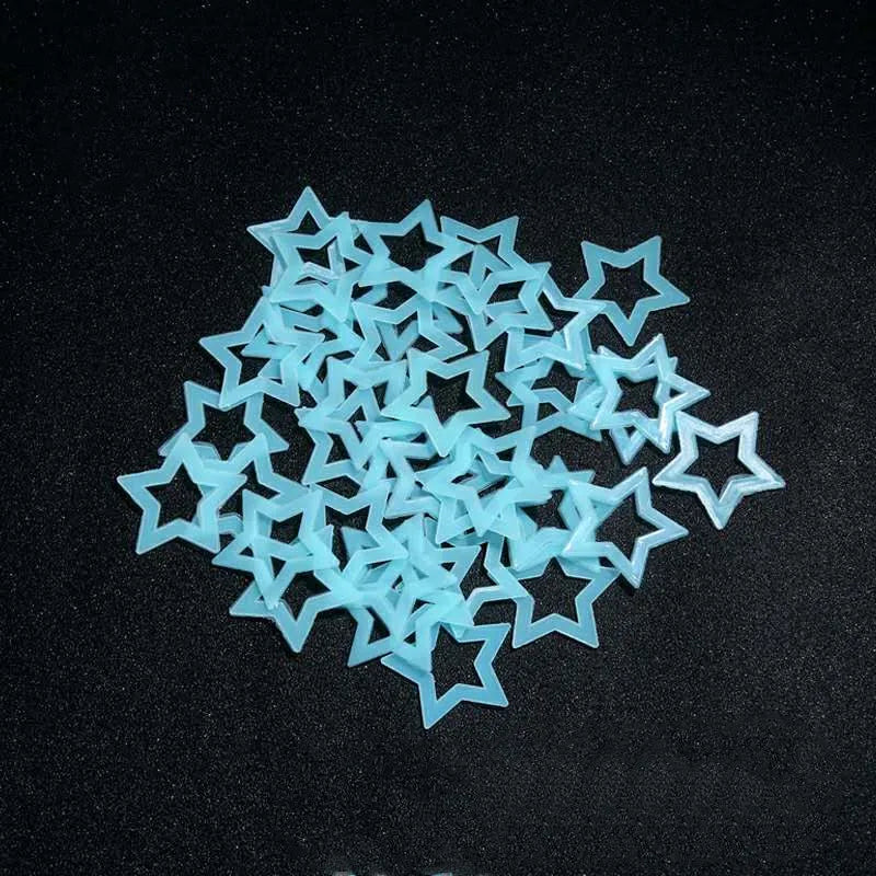 A scattered pile of light blue glow in the dark 3D star wall decals on a black surface.