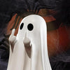 A white ghost statue decoration with outstretched hands against a dark background.