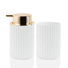A white ceramic foaming soap dispenser with a gold-colored pump and a toothbrush holder.