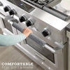 A hand grips a soft gray handle cover on a stainless steel oven door, emphasizing comfortable feel and warmth.