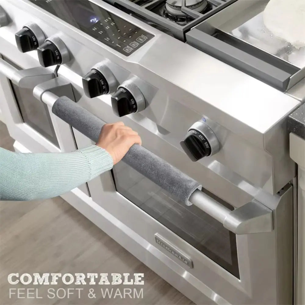 A hand grips a soft gray handle cover on a stainless steel oven door, emphasizing comfortable feel and warmth.