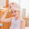 A woman is holding a pink soft absorbent hair towel on her head in a bright indoor setting.
