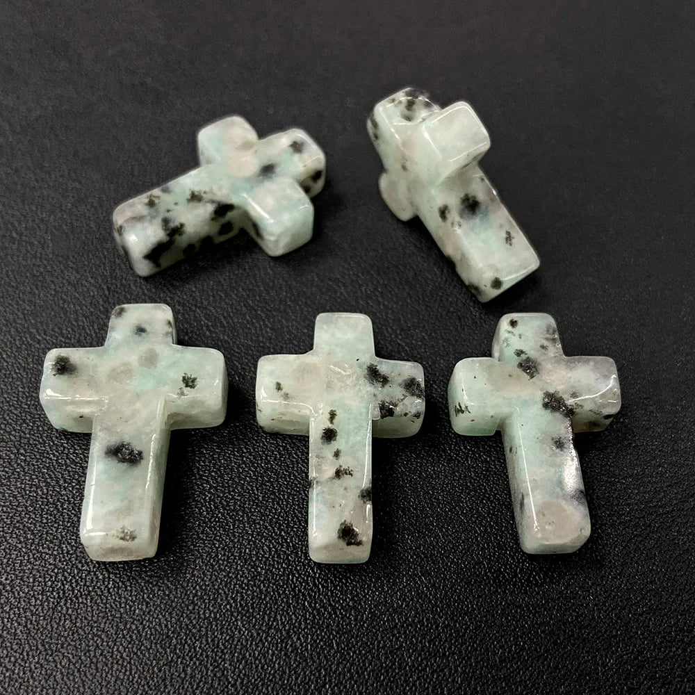 Four natural agate and jasper cross pendant charms are displayed on a dark surface.