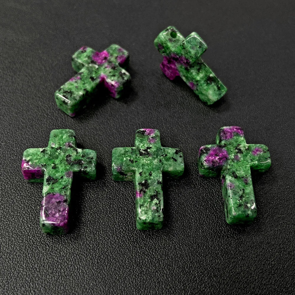 Three green and purple cross pendant charms made of natural agate and jasper are displayed on a dark surface.