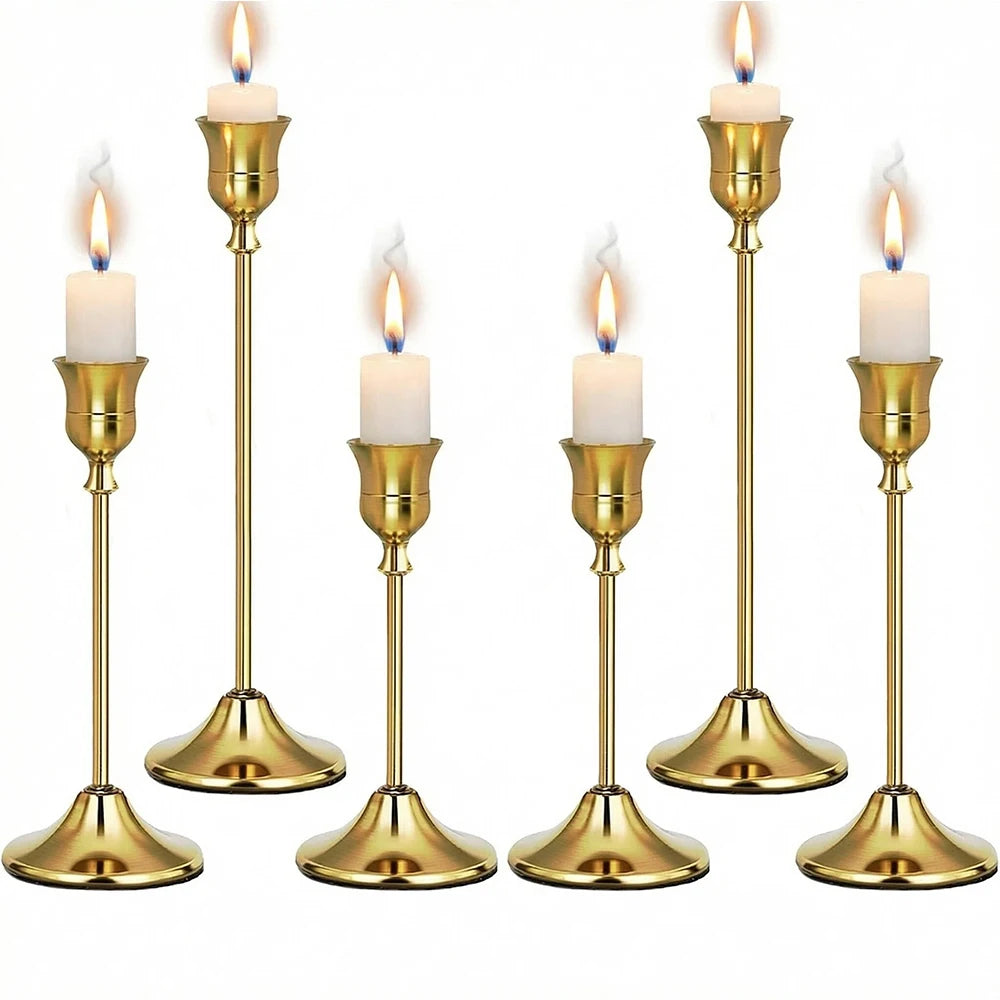 Set of six gold weighted metal taper candlestick holders with white candles
