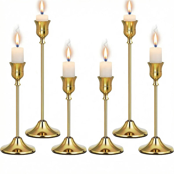 Set of six gold weighted metal taper candlestick holders with white candles