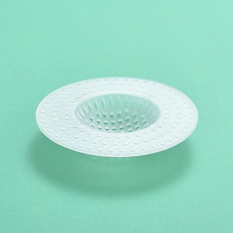 A white kitchen sink drain strainer and hair catcher with a perforated mesh design.