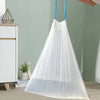 A white sheer drawstring trash bag hanging, with a blue cord, displayed next to a white cabinet and a potted plant.